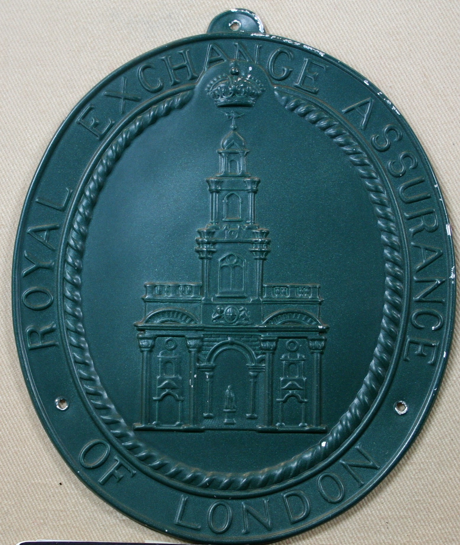 An oval green metal fire mark reading 'Royal Exchange Assurance of London,' with a crown above and an engraved image of the Royal Exchange building at the center.