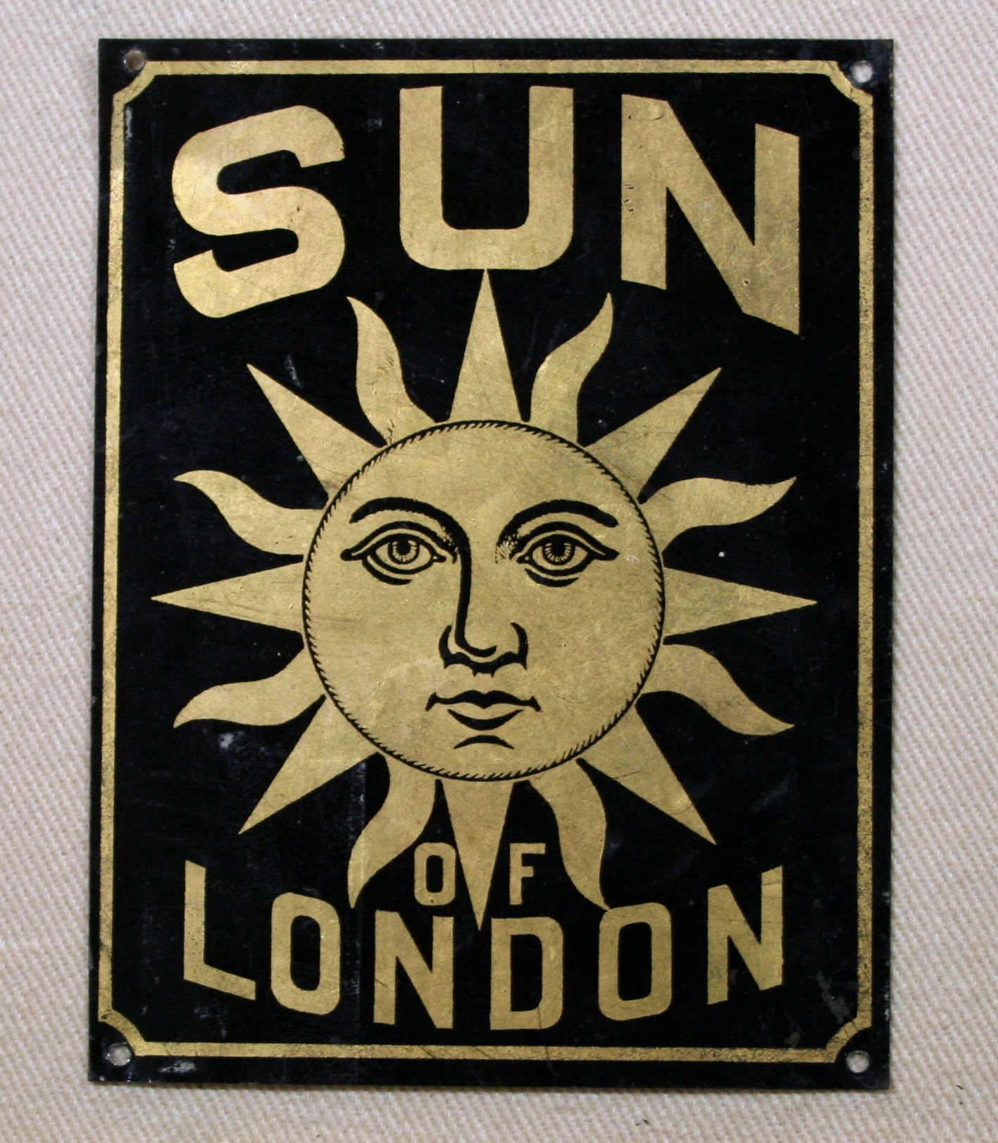 A tin fire mark lettered SUN OF LONDON around a gilded sun face, the plate the Sun Insurance Office fixed to a building to show whose policy covered it